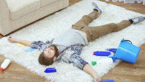 Man laying on Carpet with cleaning products around him