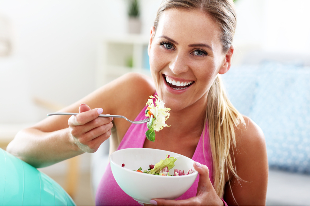 Woman smiling while eating a salad